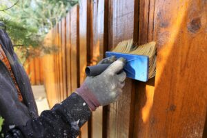 person-staining-a-fence