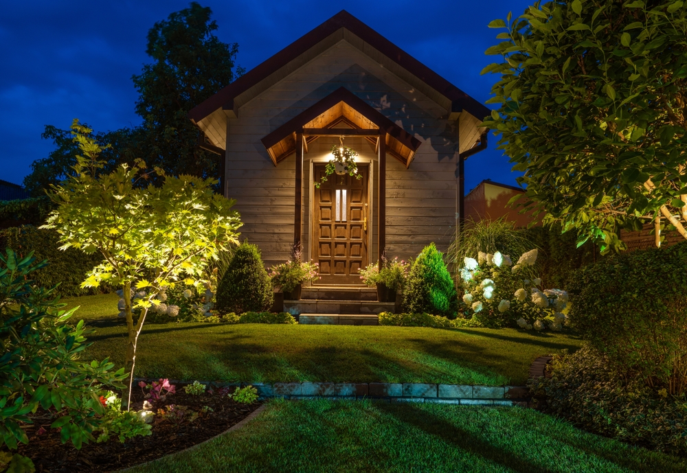 Front of illuminated rustic garden shed and beautiful backyard garden with led lighting installed